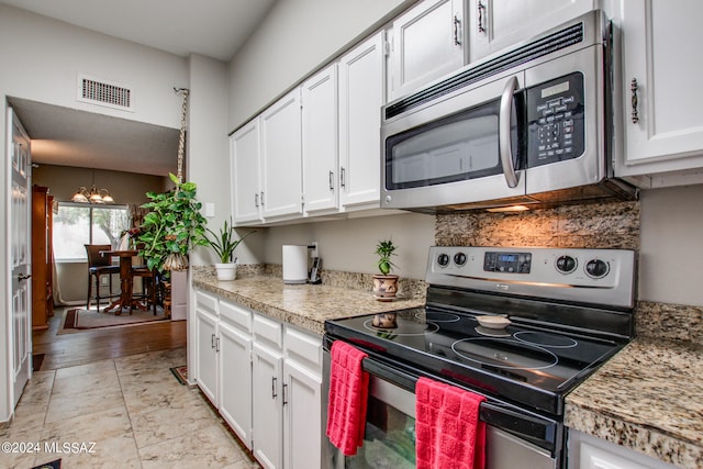 kitchen featuring appliances with stainless steel finishes, white cabinetry, a chandelier, and light hardwood / wood-style flooring