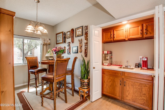 dining room featuring a textured ceiling, light hardwood / wood-style flooring, a chandelier, and sink