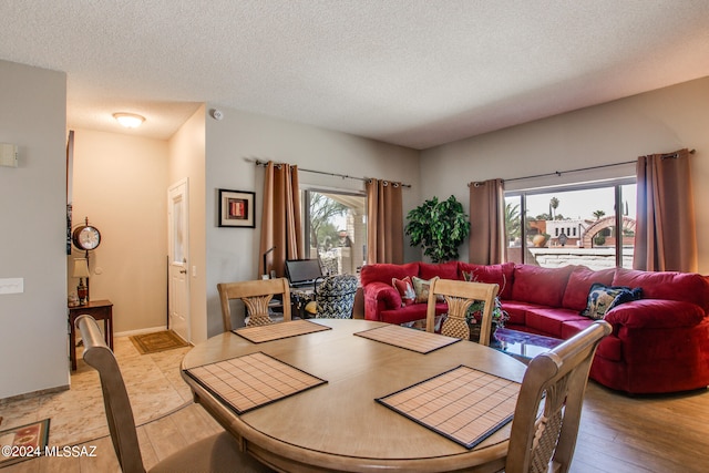 dining area featuring a textured ceiling and light hardwood / wood-style floors