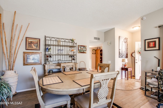 dining area with a textured ceiling and hardwood / wood-style flooring