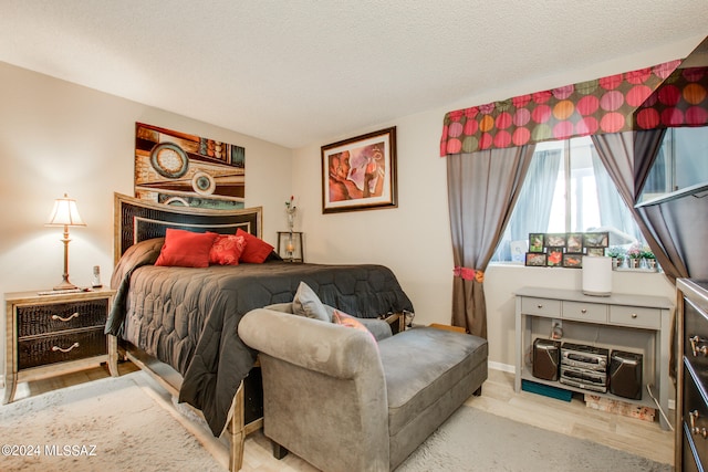 bedroom with a textured ceiling and light hardwood / wood-style flooring