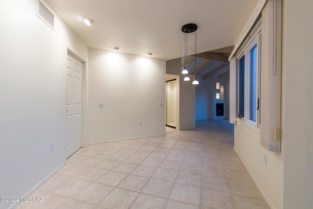 unfurnished room with beam ceiling and light tile patterned floors