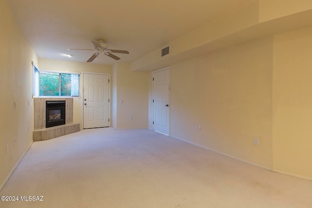 unfurnished living room featuring light carpet, a tile fireplace, and ceiling fan