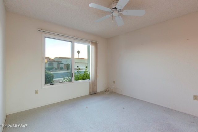 carpeted spare room with a textured ceiling and ceiling fan