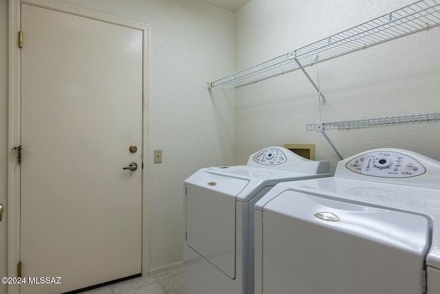 clothes washing area with independent washer and dryer and light tile patterned flooring