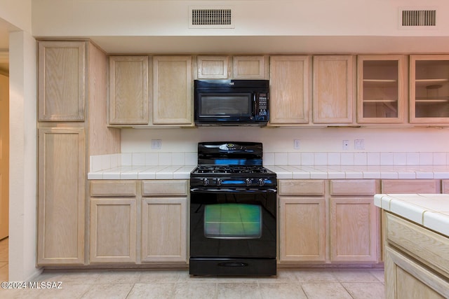 kitchen featuring light brown cabinets, tile counters, and black appliances