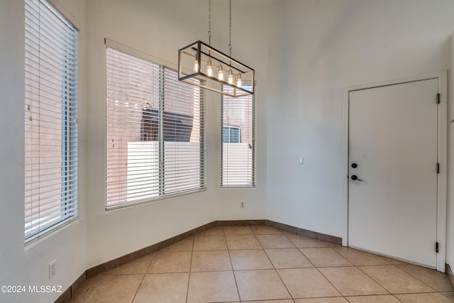 unfurnished dining area with an inviting chandelier, plenty of natural light, and light tile patterned flooring