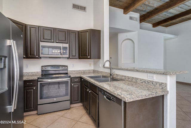 kitchen featuring appliances with stainless steel finishes, light tile patterned flooring, kitchen peninsula, beam ceiling, and sink