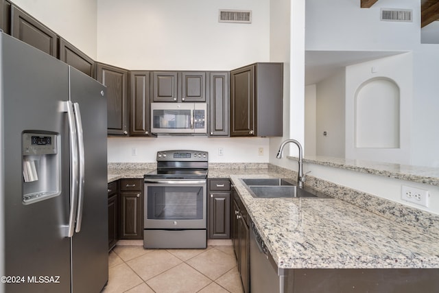 kitchen featuring light stone countertops, stainless steel appliances, light tile patterned flooring, and sink