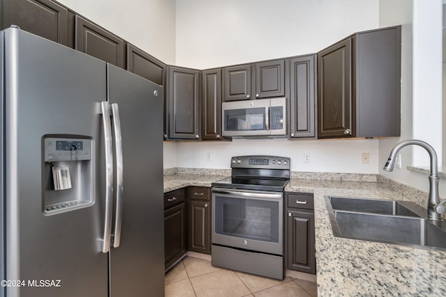 kitchen with dark brown cabinets, light tile patterned flooring, sink, and stainless steel appliances