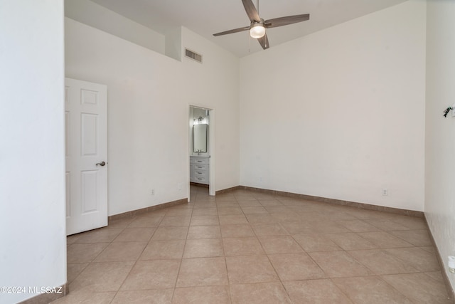 unfurnished room featuring a high ceiling, ceiling fan, and light tile patterned floors