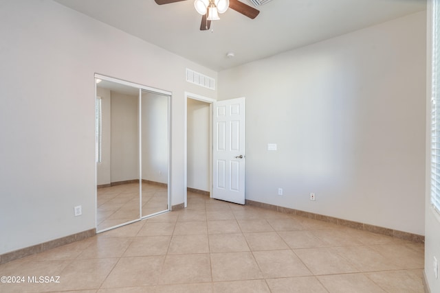 unfurnished bedroom with ceiling fan, light tile patterned flooring, and a closet