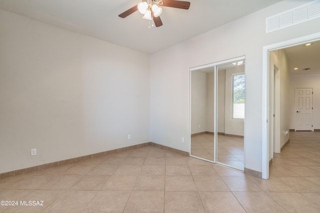 unfurnished bedroom featuring light tile patterned floors, ceiling fan, and a closet