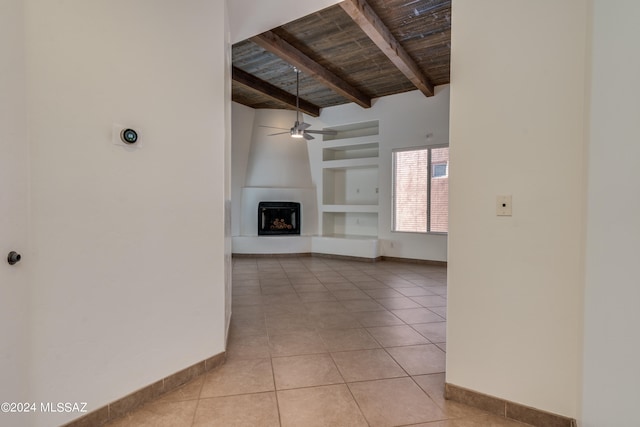 unfurnished living room with ceiling fan, beamed ceiling, light tile patterned flooring, wood ceiling, and a large fireplace