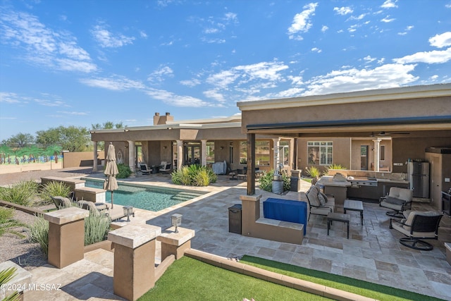 view of swimming pool featuring a patio area, an outdoor living space, an outdoor kitchen, and ceiling fan