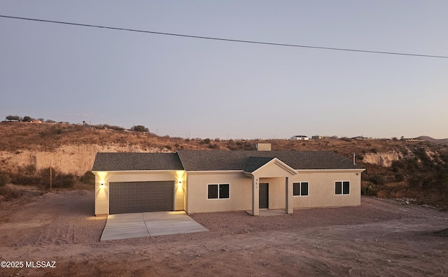 view of front of home featuring driveway, a garage, and stucco siding