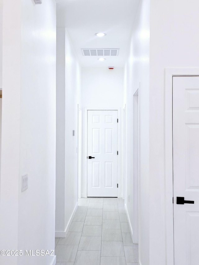 corridor with visible vents, baseboards, and light tile patterned floors