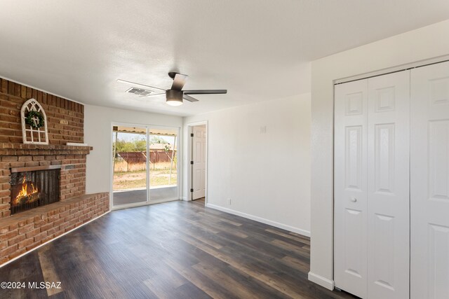 unfurnished living room with a brick fireplace, dark hardwood / wood-style floors, and ceiling fan