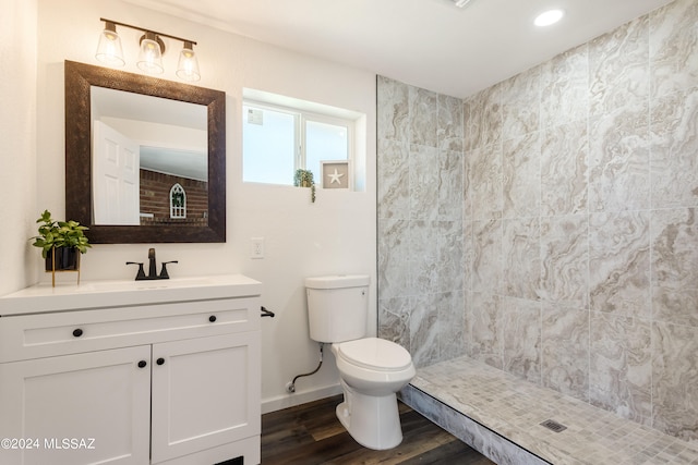 bathroom with vanity, toilet, wood-type flooring, and tiled shower