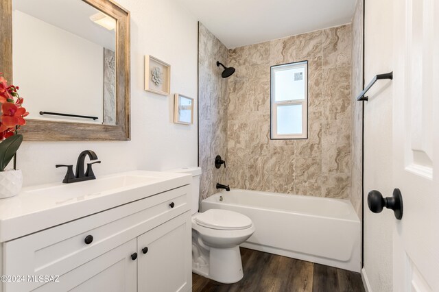 full bathroom featuring tiled shower / bath, vanity, hardwood / wood-style floors, and toilet