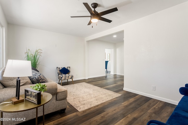 living room featuring dark wood-type flooring and ceiling fan