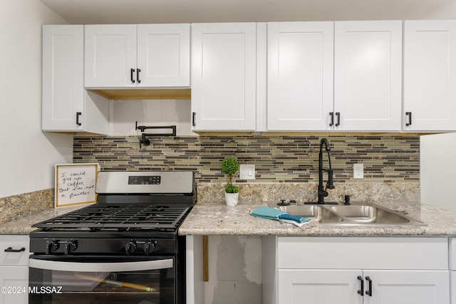 kitchen featuring light stone countertops, sink, backsplash, stainless steel range with gas stovetop, and white cabinetry