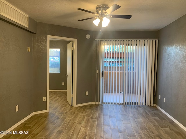 empty room with ceiling fan, a textured ceiling, and wood-type flooring