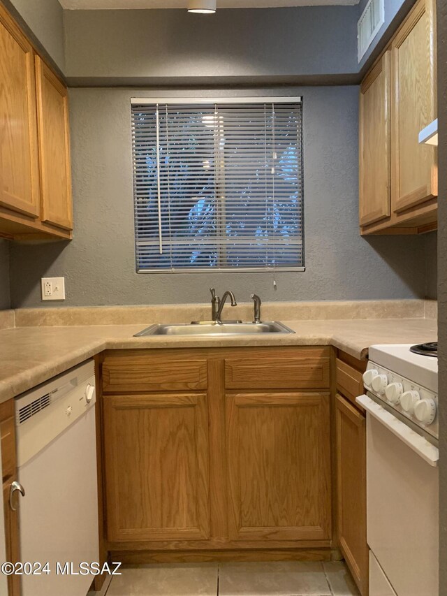 kitchen featuring white appliances, sink, and light tile patterned floors