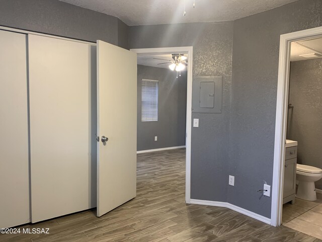 unfurnished bedroom featuring wood-type flooring, electric panel, and ensuite bathroom