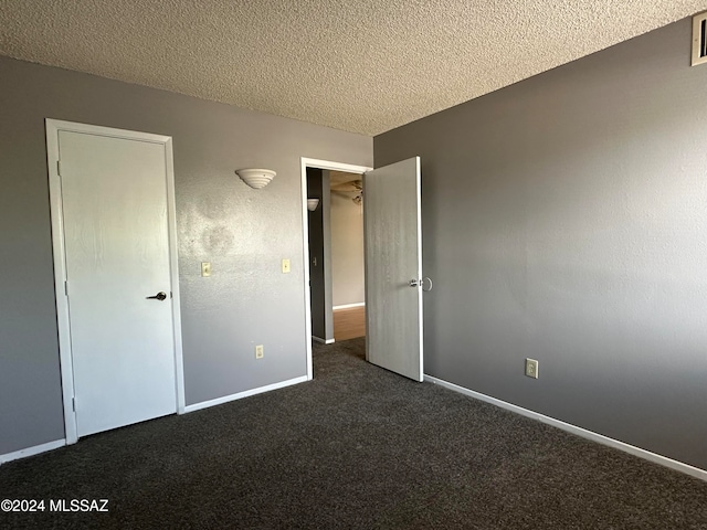 unfurnished bedroom featuring a textured ceiling and dark colored carpet