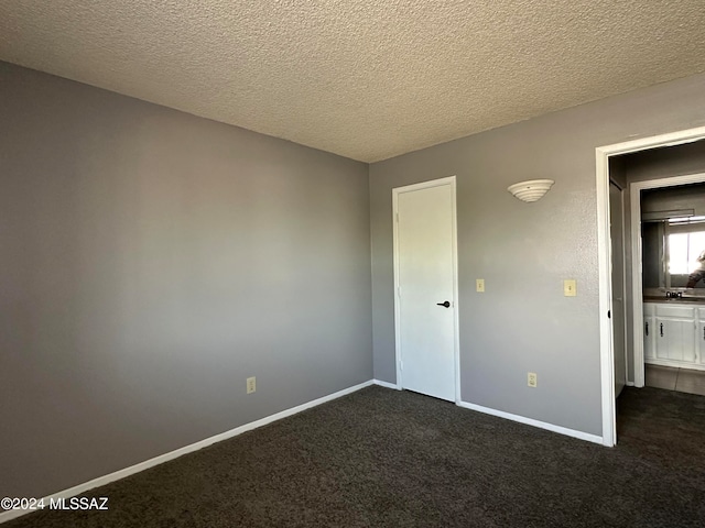 unfurnished bedroom featuring a textured ceiling and dark colored carpet