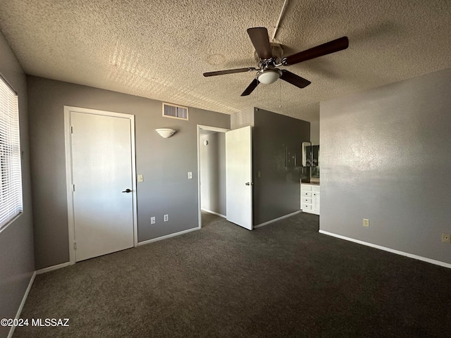 unfurnished bedroom featuring a textured ceiling, dark colored carpet, and ceiling fan