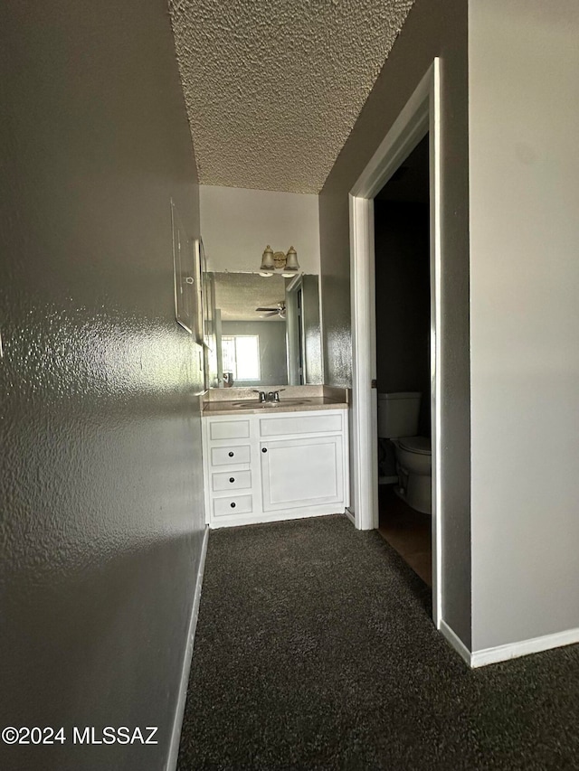 bathroom featuring a textured ceiling, vanity, and toilet