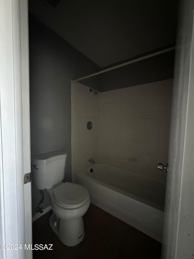 bathroom with tiled shower / bath combo, toilet, and tile patterned floors