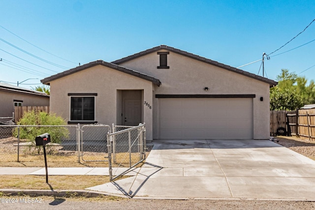 view of front of property with stucco siding, fence, driveway, a gate, and a garage