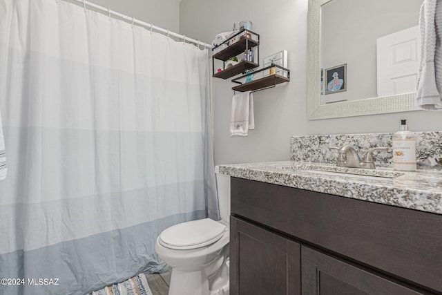 bathroom with walk in shower, vanity, and toilet