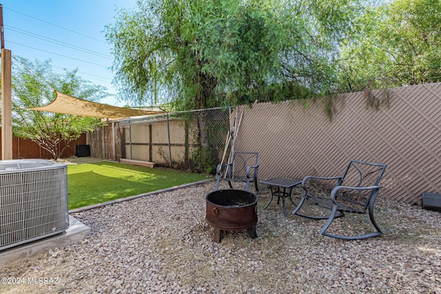 view of yard with a fenced backyard, a fire pit, and central AC unit