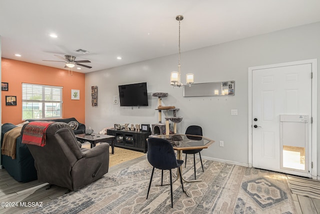 living room with ceiling fan with notable chandelier and hardwood / wood-style floors