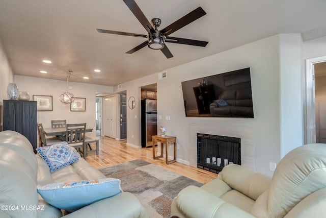 living room with light hardwood / wood-style floors, a fireplace, and ceiling fan