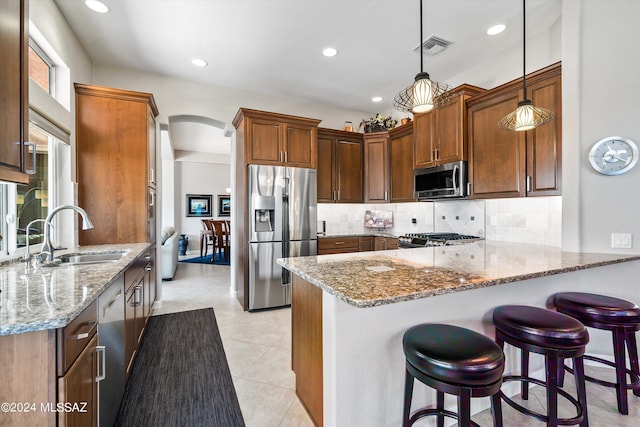 kitchen featuring kitchen peninsula, sink, light stone counters, and stainless steel appliances