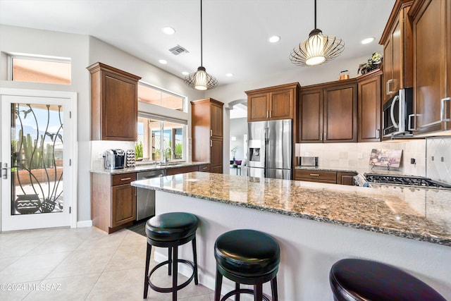 kitchen featuring appliances with stainless steel finishes, pendant lighting, dark stone countertops, and sink