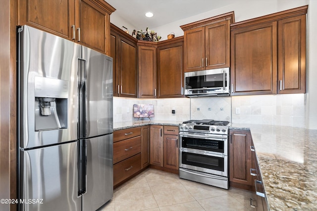 kitchen with light stone counters, decorative backsplash, light tile patterned floors, and stainless steel appliances