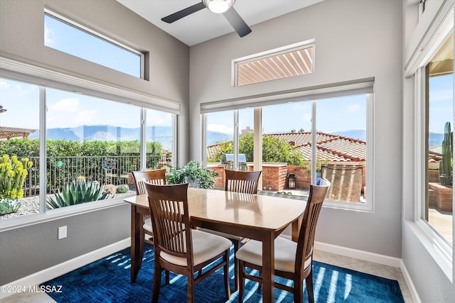 sunroom featuring ceiling fan, a wealth of natural light, and a mountain view