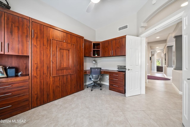 tiled office space featuring ceiling fan and built in desk