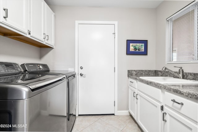 clothes washing area with washing machine and dryer, cabinets, light tile patterned flooring, and sink