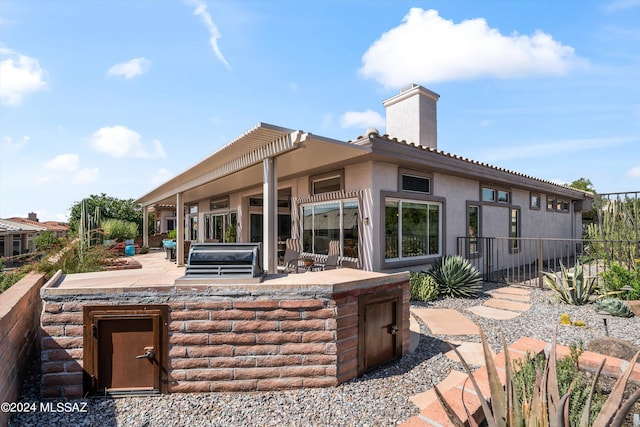 back of property featuring an outdoor kitchen and a patio