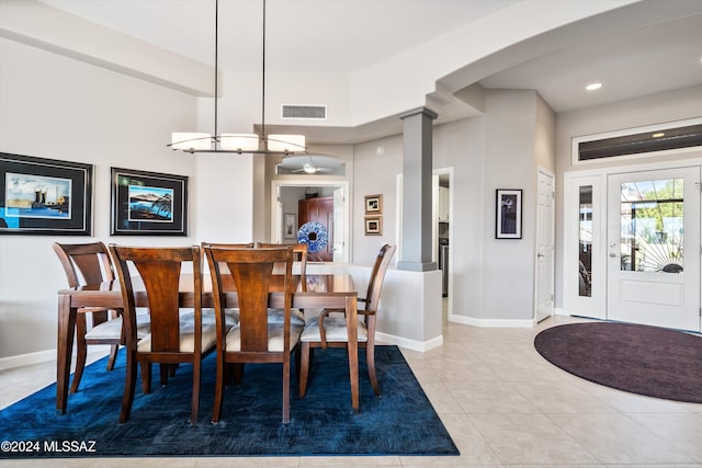 tiled dining space featuring decorative columns and a towering ceiling