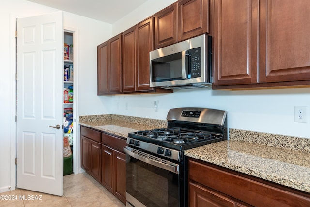 kitchen featuring light tile patterned floors, light stone countertops, and appliances with stainless steel finishes