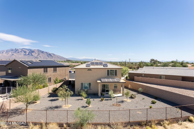 rear view of property featuring a mountain view and solar panels