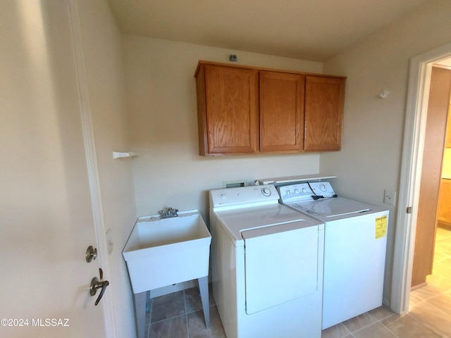 clothes washing area featuring light tile patterned floors, cabinets, sink, and independent washer and dryer